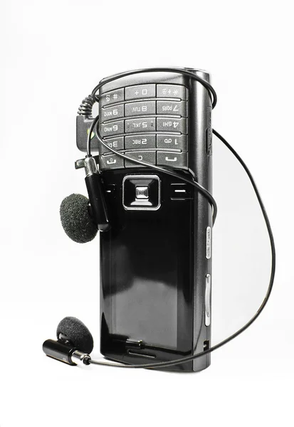 Teléfono móvil con auriculares en bgrnd blanco Imagen de stock