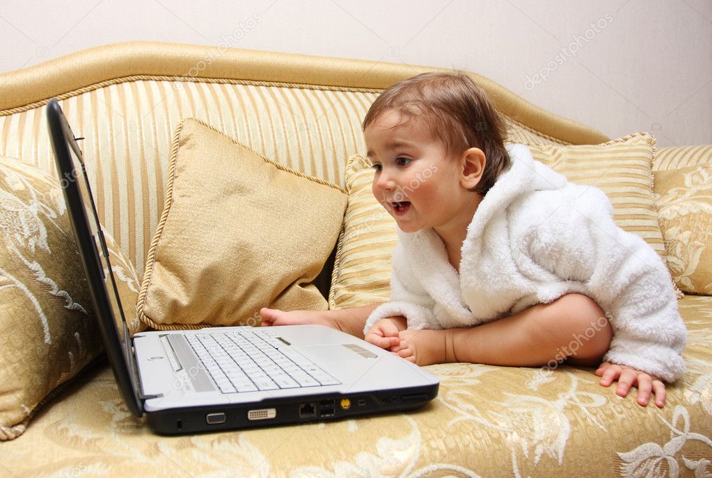 Baby boy with laptop on sofa