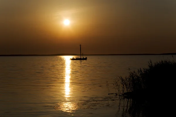 stock image Boat sailing through sunset lagoon