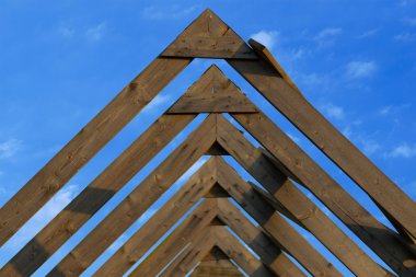 Wooden roof beams under blue skies clipart