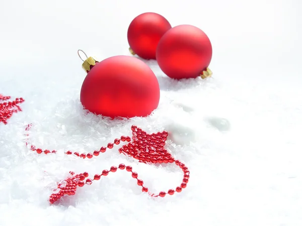 Três bolas vermelhas e estrelas na neve — Fotografia de Stock