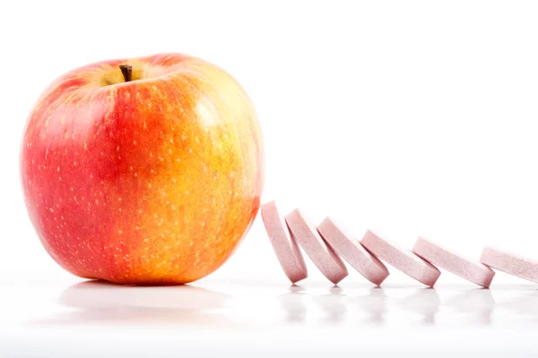 Vitamin pills dominoes, stopped by apple — Stock Photo, Image