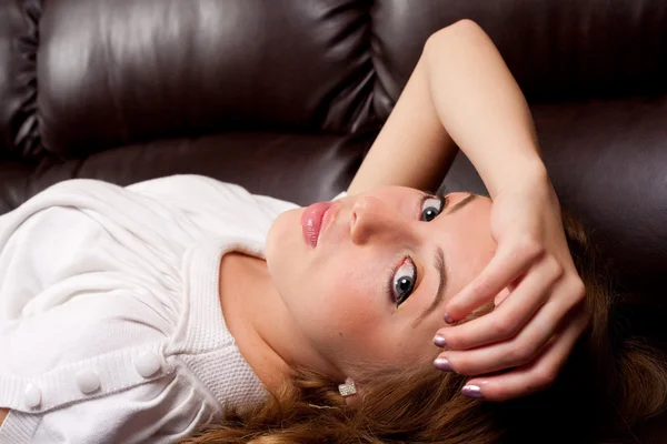 Vacker blondin i en läder soffa — Stockfoto