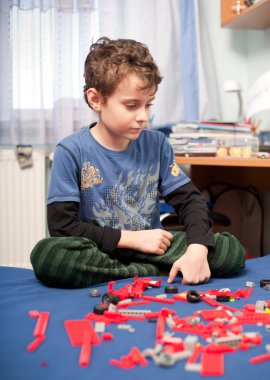 Cute kid playing with plastic blocks clipart