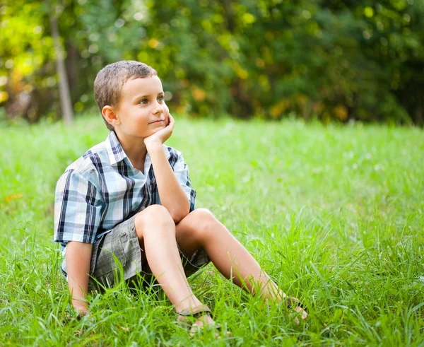 Симпатичный ребенок сидит в траве — стоковое фото