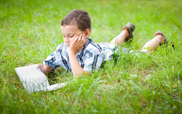 Симпатичный ребенок читает книгу на открытом воздухе — стоковое фото