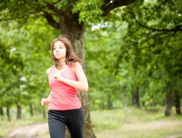 Mulher correndo através de uma floresta — Fotografia de Stock