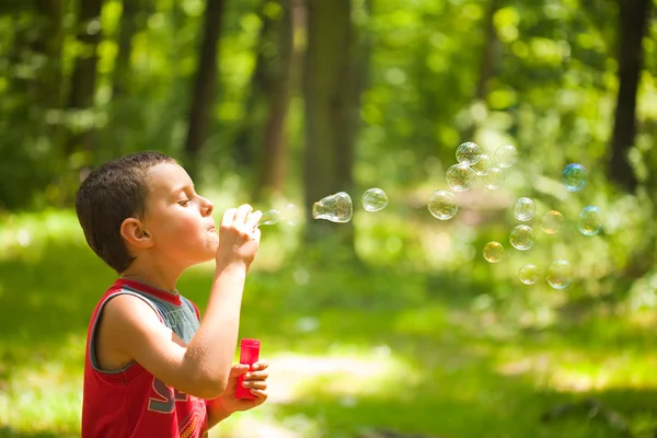 Cute kid blowing soap bubbles — Stock Photo, Image