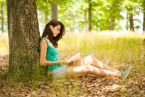 Brunetka dziewczynka czytanie książki na zewnątrz — Zdjęcie stockowe