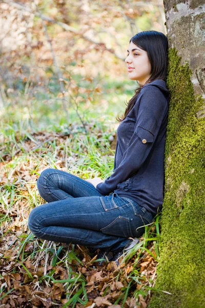Schönes Mädchen in der Nähe eines Baumstammes — Stockfoto