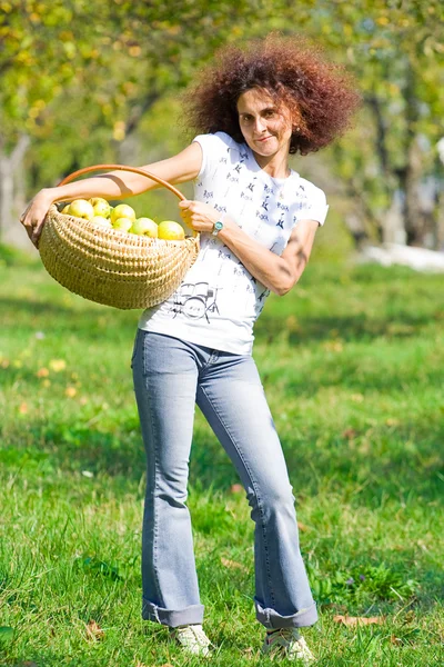 Hübsche Dame mit einem Korb voller Äpfel — Stockfoto