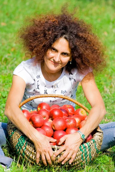 Frau mit Korb voller Äpfel — Stockfoto
