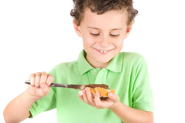 Boy spreading peanuts butter on bread — Stock Photo, Image