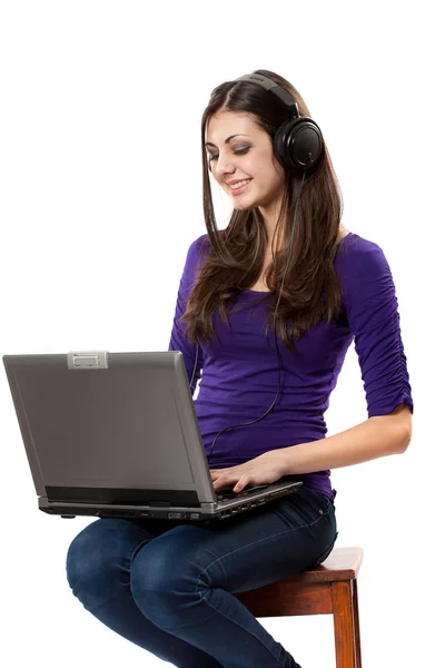 Brunett lyssnar musik från laptop — Stockfoto