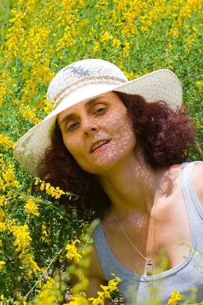 Señora con sombrero en un campo de flores —  Fotos de Stock