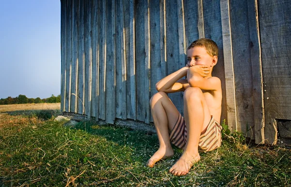 Мальчик сидит у стены — стоковое фото