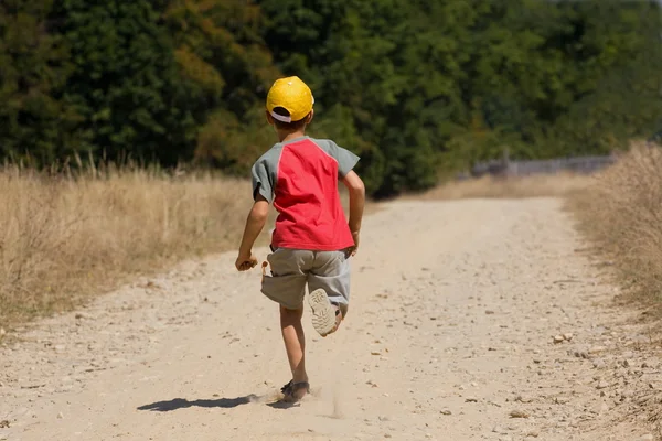 Мальчик бежит по пыльной дороге — стоковое фото