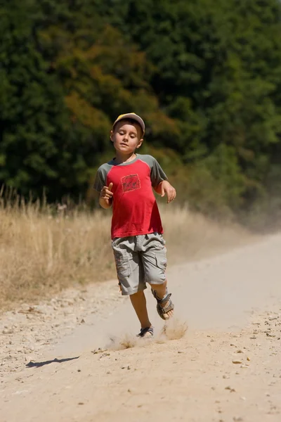 ほこりっぽい道を走っている少年 — ストック写真