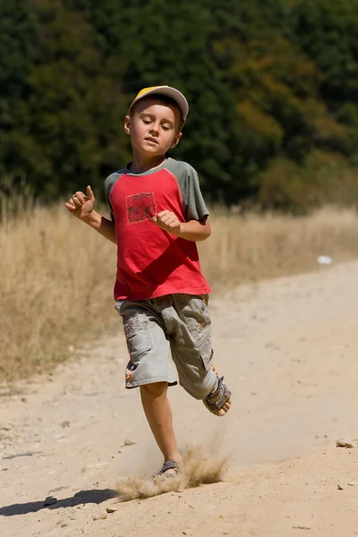 Ragazzo che corre su strada polverosa — Foto Stock
