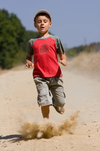 Junge läuft auf staubiger Straße — Stockfoto