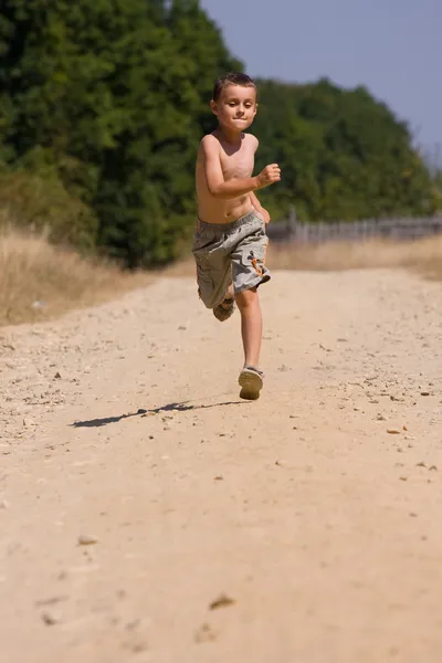 Rapaz a correr na estrada empoeirada — Fotografia de Stock