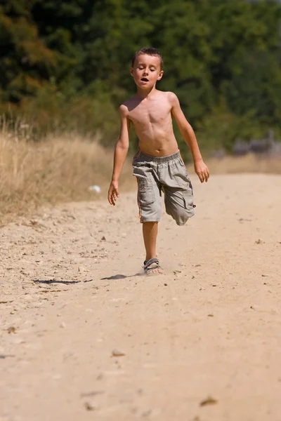 Хлопчик біжить по пиловій дорозі — стокове фото