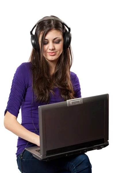 Brunett lyssnar musik från laptop — Stockfoto