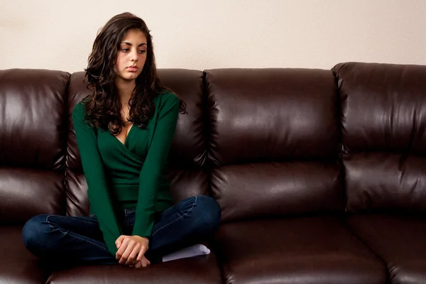 Jeune femme sur un canapé en cuir — Photo