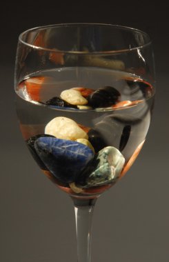 Glass with colored stones and water clipart