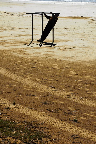 Man doen parallel bars op het strand — Stockfoto