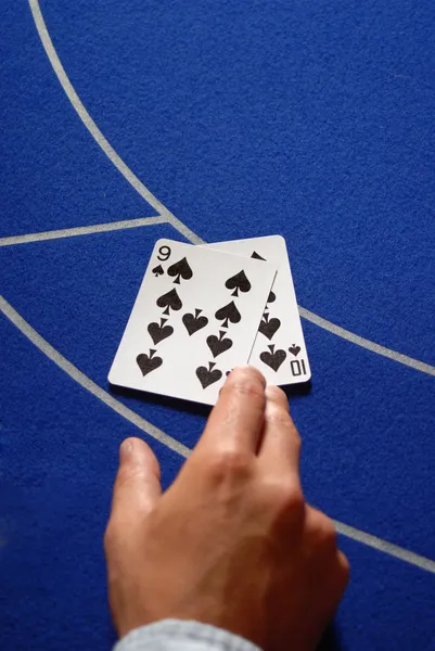 Zwei Karten in der Hand auf einem Casino-Tisch — Stockfoto