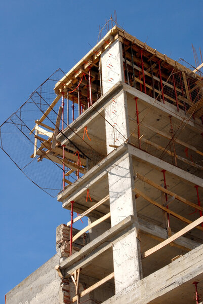 Detail of the upper part of a building under construction on a blue sky background