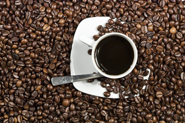 Tasse mit Kaffee auf Teller und Bohnen — Stockfoto