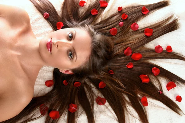 Schöne Frau mit roten Blütenblättern — Stockfoto