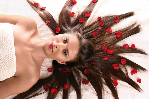 Hermosa mujer con pétalos de flores rojas —  Fotos de Stock