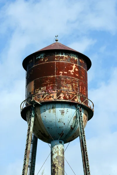 Antigua torre de agua oxidada contra el cielo azul — Foto de Stock