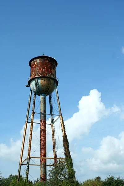 Vecchia torre d'acqua arrugginita contro il cielo blu — Foto Stock