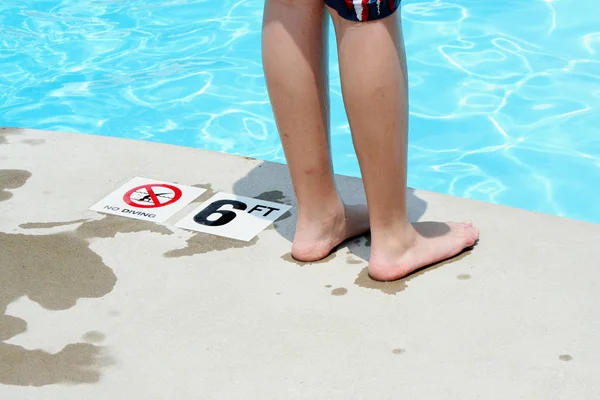 Teenage boy standing by a swimming pool — Stock Photo, Image