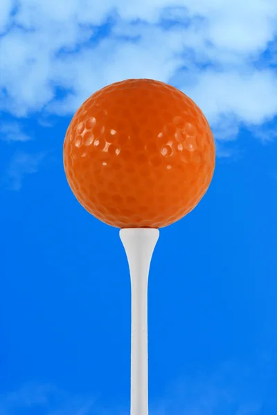 Oranje golfbal tegen blauwe hemel — Stockfoto