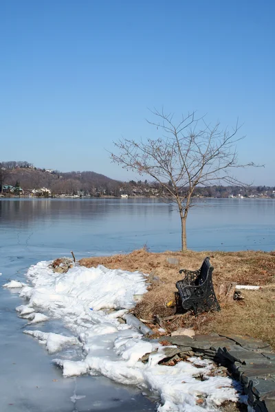 Старая пустая скамейка на замёрзшем озере — стоковое фото