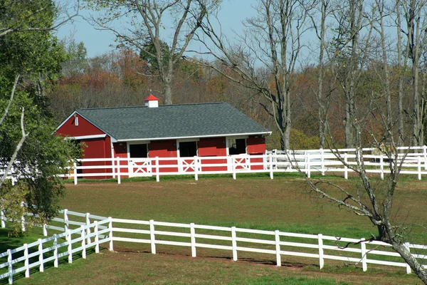 Červená stodola a bílý plot — Stock fotografie
