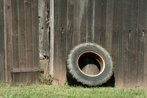 Tire leaning on a old barn — Stock Photo, Image