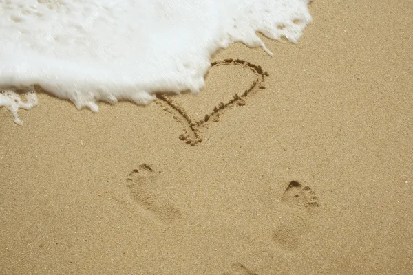 Herz und Fußabdrücke im Sand — Stockfoto