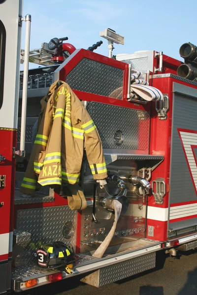Caminhão de bombeiros com casaco e capacete — Fotografia de Stock