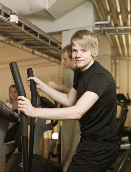 Young man using an exercise machine — Stock Photo, Image