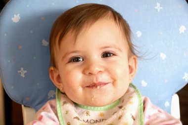 Smiling cute baby girl eating cereal clipart