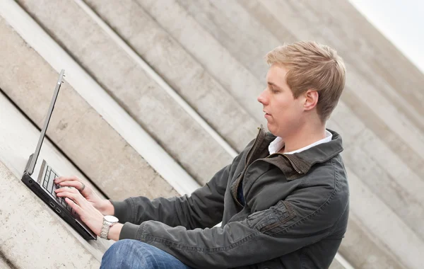 Jonge blonde man met laptop — Stockfoto