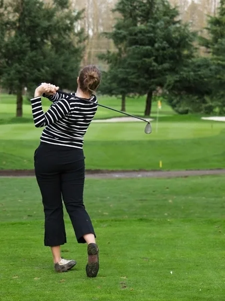 Woman golfer swinging a golf club — Stock Photo, Image