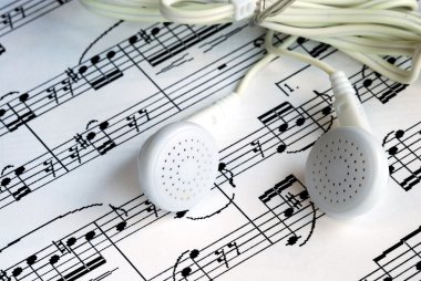 An ear phone on the top of a music sheet clipart