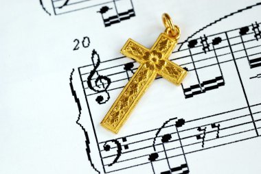 A golden cross on the music sheet clipart